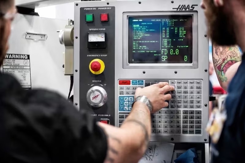Machinist at Haas CNC control panel loading program